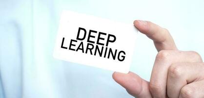 Man in blue sweatshirt holding a card with text DEEP LEARNING, business concept photo