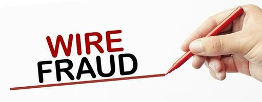 WIRE FRAUD on white background and hand with red marker photo