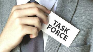 Businessman putting a card with text TASK FORCE in the pocket photo