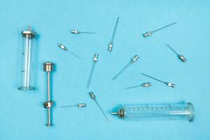 view of hypodermic needles and syringes on blue photo