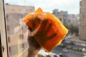 hand wipes outdoor side of window glass with rag photo