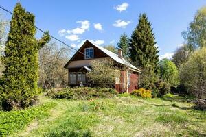 view of wooden cottage in overgrown courtyard photo