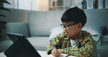 asiático genio chico utilizar tableta haciendo deberes en vivo habitación foto