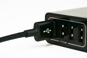 USB un cargando cable en móvil teléfono cargador Puerto en blanco fondo, móvil teléfono equipo concepto. foto