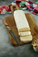 Raw tempeh or tempe, tempeh slices on wooden plate and raw soybean seeds. Tempe is a traditional Indonesian food made from fermented soybeans. photo