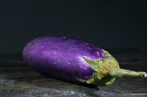 Bright Purple Fresh healthy eggplants on dark wooden background photo