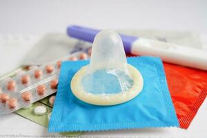 Pregnancy test with birth control pills and condom for female on calendar, ovulation day. photo