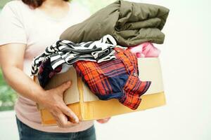 Clothes donations in cardboard box for volunteer. photo