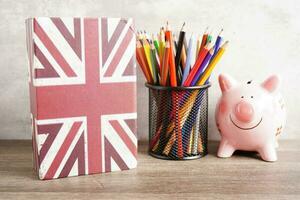 English book and piggy bank with pencil, learning and tutorial for foreigner. photo