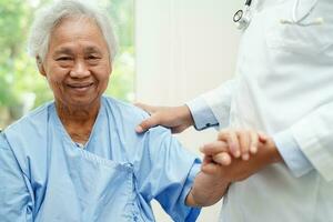 Doctor holding hands Asian elderly woman patient, help and care in hospital. photo