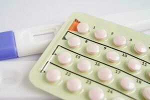 Pregnancy test with birth control pills for female on calendar, ovulation day. photo