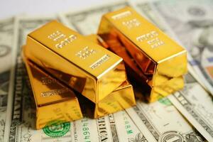 Gold bars on US dollar banknote money, finance trading investment business currency concept. photo