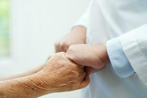 Doctor holding hands Asian elderly woman patient, help and care in hospital. photo