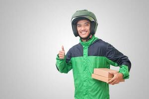 Portrait of Asian online courier driver wearing green jacket and helmet delivering package and box for customer. Isolated image on white background photo