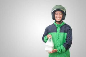 Portrait of Asian online taxi driver wearing green jacket and helmet holding food wrapped in foam plastic box. Isolated image on white background photo