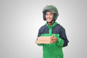retrato de asiático en línea mensajero conductor vistiendo verde chaqueta y casco entregando paquete y caja para cliente. aislado imagen en blanco antecedentes foto