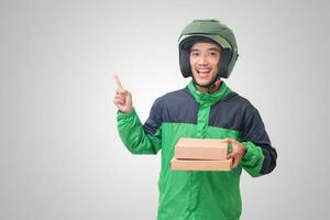 Portrait of Asian online courier driver wearing green jacket and helmet delivering package and box for customer. Isolated image on white background photo