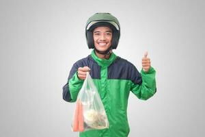 retrato de asiático en línea Taxi conductor vistiendo verde chaqueta y casco entregando el vegetales desde tradicional mercado y señalando con dedo. aislado imagen en blanco antecedentes foto