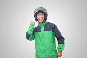 Portrait of Asian online taxi driver wearing green jacket and helmet showing good job sign, thumb up. Isolated image on white background photo