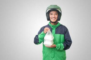 retrato de asiático en línea Taxi conductor vistiendo verde chaqueta y casco participación comida envuelto en espuma el plastico caja. aislado imagen en blanco antecedentes foto