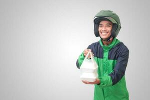 retrato de asiático en línea Taxi conductor vistiendo verde chaqueta y casco participación comida envuelto en espuma el plastico caja. aislado imagen en blanco antecedentes foto