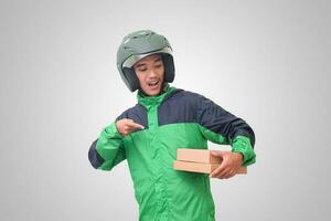 Portrait of Asian online courier driver wearing green jacket and helmet delivering package and box for customer. Isolated image on white background photo