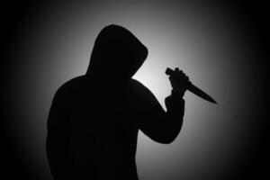 misterioso hombre vistiendo negro capucha participación un cuchillo a puñalada alguien. crímenes y criminalidad concepto foto