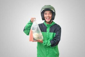 Portrait of Asian online taxi driver wearing green jacket and helmet delivering the vegetables from traditional market and pointing with finger. Isolated image on white background photo