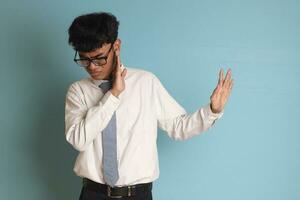 Indonesian senior high school student wearing white shirt uniform with gray tie forming a hand gesture to avoid something. Isolated image on blue background photo