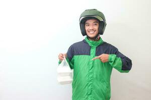 Portrait of Asian online taxi driver wearing green jacket and helmet holding food wrapped in foam plastic box. Isolated image on white background photo