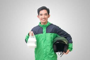 Portrait of Asian online taxi driver wearing green jacket and helmet holding food wrapped in foam plastic box. Isolated image on white background photo