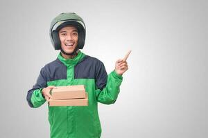 Portrait of Asian online courier driver wearing green jacket and helmet delivering package and box for customer. Isolated image on white background photo