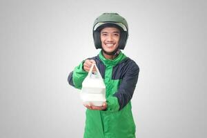 retrato de asiático en línea Taxi conductor vistiendo verde chaqueta y casco participación comida envuelto en espuma el plastico caja. aislado imagen en blanco antecedentes foto