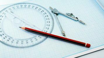On blue graph paper are compasses, protractor, ruler, and a pencil photo