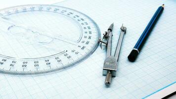 On blue graph paper are compasses, protractor, ruler, and a pencil photo