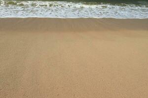 Water foam with smooth sand. Ocean shore with sandy beach and advancing wave. photo