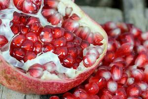 Red Pomegranate seeds on the wooden background. Healthful natural fruits for cancer patient photo