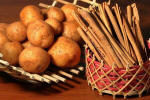 A lot of potatoes with Cinnamon Sticks on wooden background. Harvest of potatoes. Vegetables for a healthy diet. photo