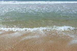 Water foam with smooth sand. Ocean shore with sandy beach and advancing wave. photo