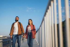 contento Pareja participación manos y caminando en peatonal pasarela turistas son Turismo en el ciudad. foto