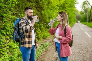 Happy couple hiking in nature and drinking water. Couple enjoying their vacation. photo