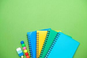 Collection different bright school stationery  and notebooks on green background, flat lay. Back to school concept. photo