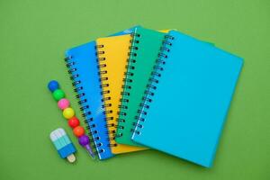 Collection different bright school stationery  and notebooks on green background, flat lay. Back to school concept. photo