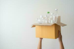 People launch a campaign to recycle used empty plastic bottles. Hands holding cardboard box full with plastic bottle ready to recycle. Concept of reuse, reduce, recycle to save the environment photo