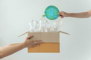 People launch a campaign to recycle used empty plastic bottles. Hands holding cardboard box full with plastic bottle ready to recycle. Concept of reuse, reduce, recycle to save the environment photo