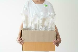 People launch a campaign to recycle used empty plastic bottles. Hands holding cardboard box full with plastic bottle ready to recycle. Concept of reuse, reduce, recycle to save the environment photo