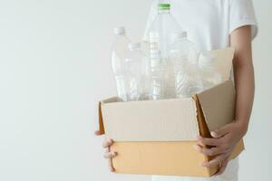 People launch a campaign to recycle used empty plastic bottles. Hands holding cardboard box full with plastic bottle ready to recycle. Concept of reuse, reduce, recycle to save the environment photo