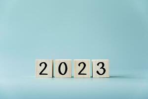 Year 2023 in wooden toy blocks and light blue background. Number in cubes concept of the year 2023. photo