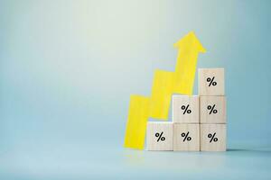 Yellow paper cut arrow going up positive trend on wooden blocks with percentages. Concept of profit increasing in percentage. photo