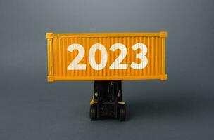 Forklift with a shipping container with 2023. Analytics forecasting of freight traffic next year. Develop infrastructure projects. Express delivery, goods transportation. Logistics. Import export. photo